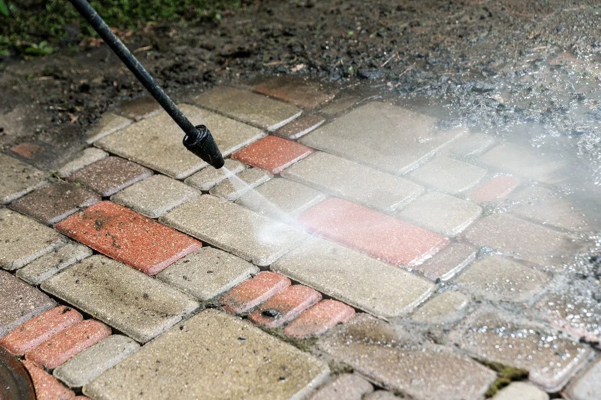 zanieczyszczenia na kostce brukowej przed garażem i rezultat czyszczenia myjką ciśnieniową Karcher 5/15 C